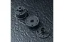 Three black plastic RC gearbox components arranged on a textured dark grey surface.