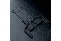 A black MST front lower deck chassis part for an RC car, shown from an overhead angle on a textured black surface.