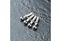 Four silver-colored metal ball studs arranged in a row on a dark, textured surface.