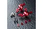 Two red anodized aluminium MST ATK V3 steering hubs with included screws, spacers, and pins on a textured dark surface.