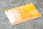 A rectangular sheet of yellow Aurora window sticker film with a reflective, iridescent texture laid on a grey surface.