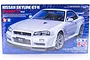 Tamiya 1/24 scale Nissan Skyline R34 GT-R V-spec II plastic model kit box art showing a white car on a blue background.