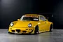 Yellow Pandora RC RWB 993 Type drift body shell mounted on a chassis with wide body kit and large rear wing.
