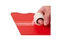 A hand applying a roll of clear hinge tape along the seam of a red foam model aircraft wing.