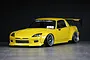 Custom painted yellow Honda S2000 RC drift car body shell with aftermarket aero kit, wide fenders, and black wheels against a dark background.