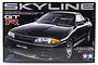 Tamiya 1/24 scale Nissan Skyline GT-R plastic model kit box art showing a black sports car on a black background.