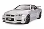 A studio shot of a 1/24 scale Tamiya Nissan Nismo R34 GT-R Z-Tune plastic model car, finished in silver with black wheels.