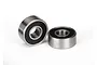 Two small metal ball bearings with black rubber seals sitting on a white background.