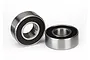 Two small metal ball bearings with black rubber seals sitting on a white background.
