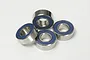 Four Tamiya 5x11x4mm rubber shielded ball bearings arranged in a cluster on a white background.
