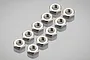 A set of ten small silver-colored metal hex nuts arranged in two rows on a reflective grey surface.