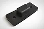 A black rubber switch cover for an RC vehicle, featuring a rectangular raised center and two mounting holes on a flat base.
