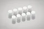 Ten small, cylindrical white urethane foam bushings arranged in two rows on a reflective grey surface.