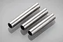 Three cylindrical metal tube spacers arranged diagonally on a light grey reflective surface.