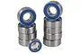 A collection of metal ball bearings with blue rubber seals arranged in two stacks and one loose bearing on a white background.