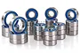 A collection of metal ball bearings with blue rubber seals arranged in stacks against a white background.