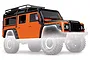Orange Traxxas TRX-4 Land Rover Defender body shell with black roof rack and accessories, shown on a faded chassis background.