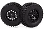 Two black off-road RC short course tires mounted on black spoke rims, shown against a white background.