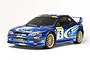 A 1/10 scale Tamiya Subaru Impreza WRC Monte Carlo '99 RC rally car model in blue with gold wheels, shown from a front three-quarter angle.