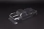 A clear, unpainted polycarbonate RC truck body shell for an ARRMA Outcast 4S, viewed from a high angle against a black background.