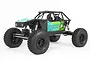 Axial Capra 1.9 Unlimited Trail Truck RC rock crawler in green, featuring a tube chassis, large off-road tires, and detailed driver figures.