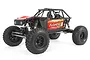 Axial Capra 1.9 Unlimited Trail Truck RC rock crawler in red, featuring a tube chassis, off-road tires, and detailed driver figures.