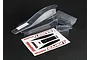 Traxxas Bandit clear unpainted RC buggy body shell with a rear wing, small accessory part, and a decal sheet on a black background.