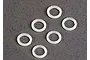 Six small, white, circular plastic washers arranged on a textured grey surface.