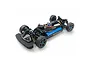 A high-angle studio shot of the Tamiya TT-02 Type SR 1/10 scale RC touring car chassis, showing the black frame, blue battery, and suspension components.