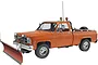 A 1/24 scale model of an orange GMC pickup truck equipped with a front-mounted snow plow, featuring chrome wheels and a roll bar with lights.