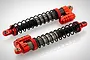 Two Rovan Baja red aluminium front piggyback shock absorbers with black springs on a white background.