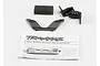 Traxxas E-Revo battery retainer clip set including plastic clips, a foam block, and an instruction sheet on a white background.