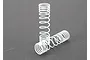 Two white progressive coil springs for RC car shocks, one standing upright and one lying horizontally on a grey surface.