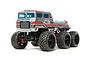 A studio shot of the Tamiya Dynahead 6x6 RC truck kit, featuring a silver cab with orange stripes, black wheels, and large off-road tires.