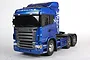 A studio shot of a blue Tamiya Scania R620 Highline 1/14 scale RC semi-truck model against a plain white background.