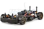 HPI Sprint 2 drift RC car chassis showing the black plastic frame, orange shock absorbers, and bronze-colored wheels on a white background.