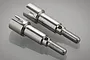 Two silver metal rear wheel axles for a BlackZon 1/12 scale RC car, shown side by side on a reflective surface.