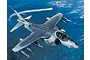 An artistic illustration of a US Marine Corps AV-8B Harrier II jet in flight over a blue sea, featuring missiles and markings.