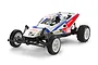 A Tamiya Grasshopper II 1/10 scale RC buggy kit, featuring a white body with blue and red racing decals, white wheels, and black off-road tires.