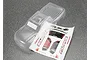 A clear, unpainted Traxxas Stampede RC truck body shell with a decal sheet included on a grey speckled surface.
