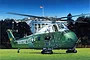 Box art illustration of a green and white VH-34D Marine One helicopter parked on a lawn in front of the White House.