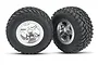 Two Traxxas off-road RC wheels with black knobby tires mounted on satin chrome five-spoke rims against a white background.