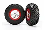 Two Traxxas RC short course wheels with black rubber tyres and satin chrome and red rims against a white background.