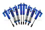 A set of eight blue anodized aluminium piggyback shock absorbers for an RC car arranged in a fan shape against a white background.