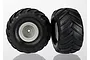 Two Traxxas Monster Jam replica RC truck wheels with black chevron-tread tyres and grey rims against a white background.