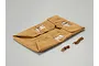 A folded tan canvas truck bed awning for a 1/10 scale RC Toyota Land Cruiser, including two small lengths of brown cord.