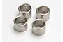 Four small, cylindrical silver-coloured metal wheel spacers arranged on a white surface.