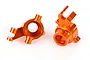 Two orange anodized aluminium steering hubs for Traxxas Maxx RC vehicle, shown from different angles against a white background.