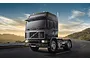 A black Volvo F16 Globetrotter truck cab driving on a winding road at sunset.