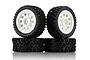 Four UDI RC rally tyres with aggressive tread patterns mounted on white multi-spoke plastic rims, arranged in a stack against a white background.